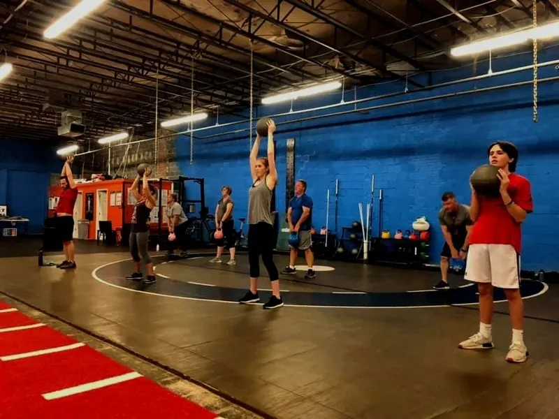 Members lifting medicine balls overhead in the gym